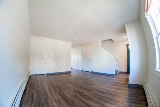an empty living room with white walls and wood floors