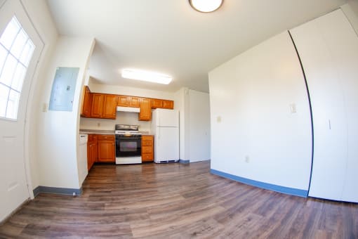 an empty living room and kitchen with wood floors and white walls