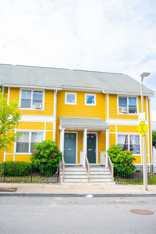 a yellow house with green bushes in front of it