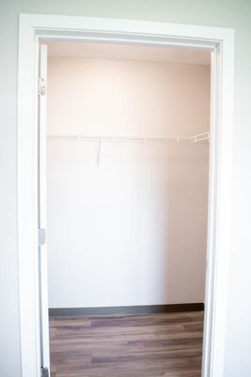 A white door is open to a room with a wooden floor.