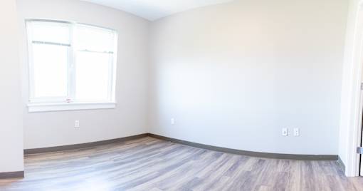 A room with a window and wooden flooring.