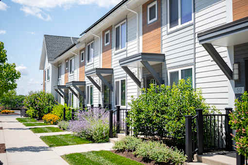 A row of townhouses with a sidewalk in front.