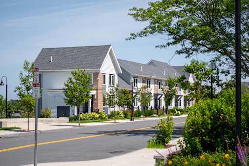 A street view of a residential area with houses and a street sign.