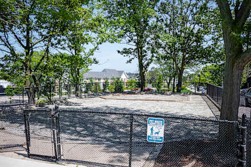 A sign on a fence in a park says "CLEAN WASTE".