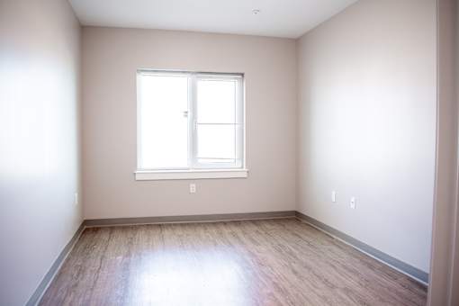 A room with a window and wooden flooring.