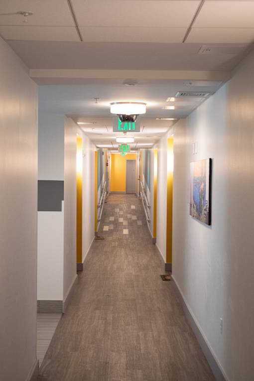 A long hallway with a green exit sign above it.