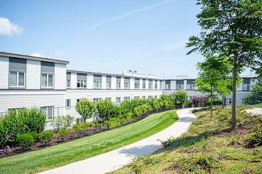 A long white building with a green lawn in front.