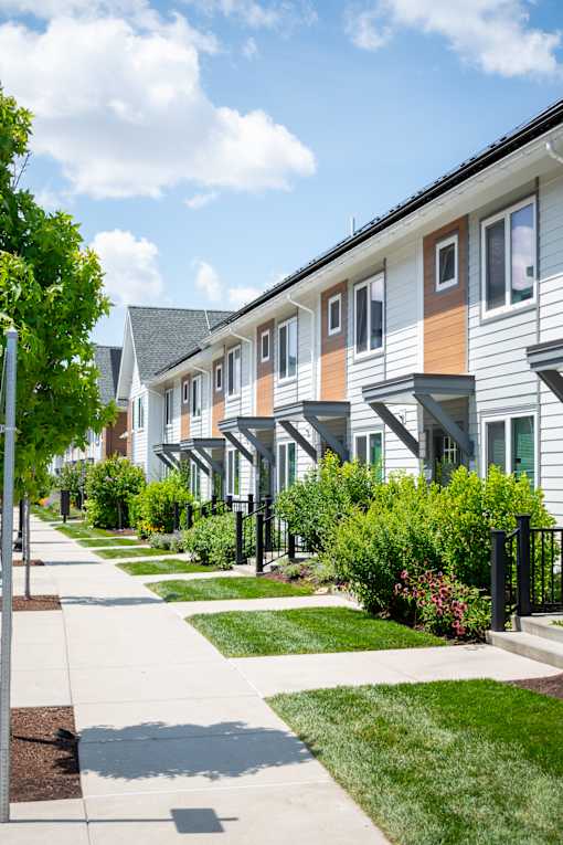 A row of houses with green lawns and trees.
