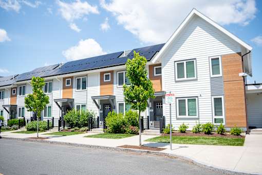 A row of houses with a red and white sign in front of the first one.