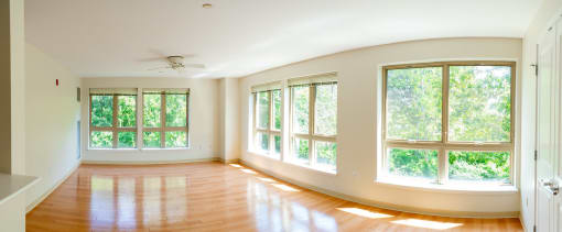 an empty room with large windows and a ceiling fan