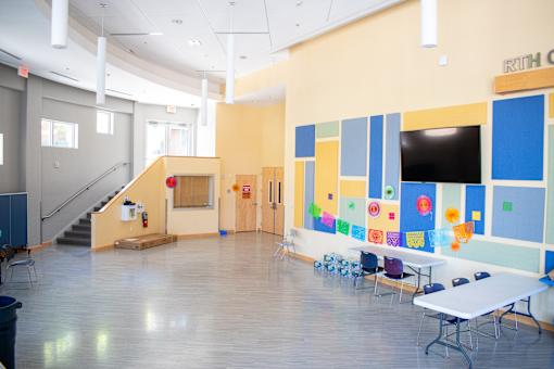 a large room with tables and chairs and a wall with a projection screen