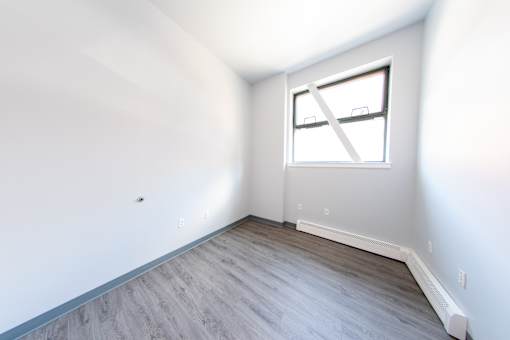 A room with a window and wooden flooring.