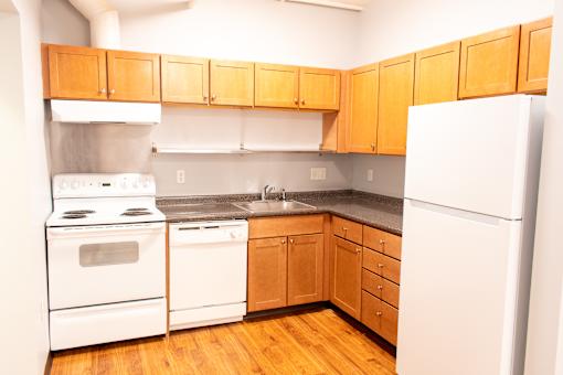 A kitchen with white appliances and wooden cabinets.