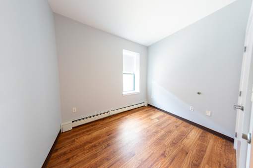 A room with a window and wooden floors.