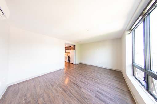 A room with wooden flooring and a window on the right side.