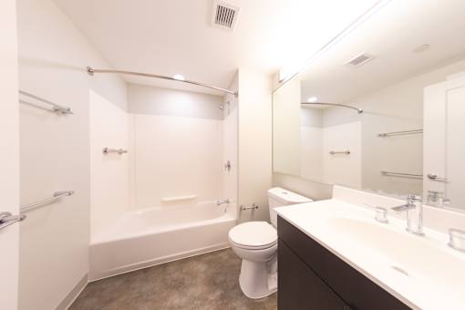 A white toilet sits in a bathroom next to a bathtub and sink.
