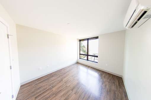 A room with a window and wooden flooring.