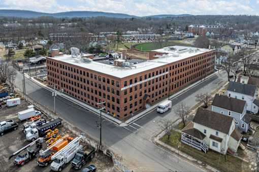A large red brick building with a parking lot in front of it.