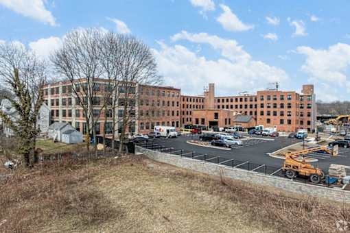 A large red brick building with a parking lot in front.