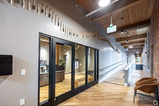 A long hallway with a brick wall on the side and a wooden ceiling.