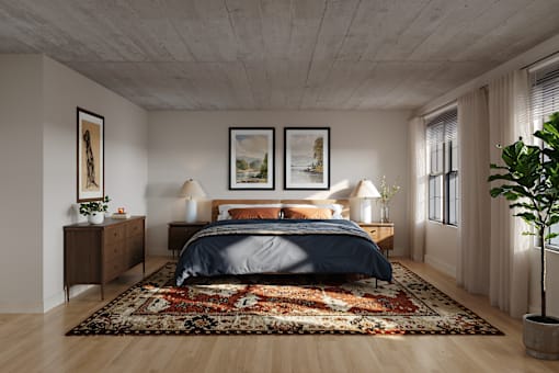 A bedroom with a large bed and a rug on the floor.