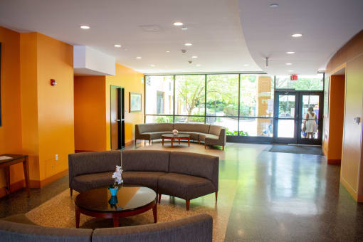 a seating area with couches and tables in front of a large window