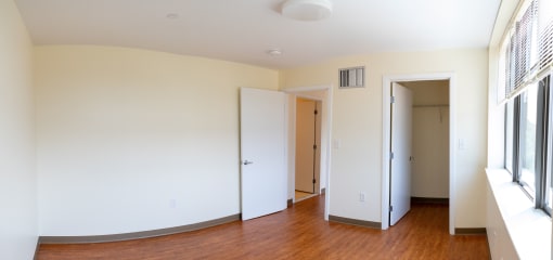a bedroom with white walls and hardwood floors