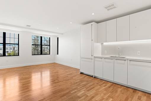 A room with white cabinets and wooden flooring.