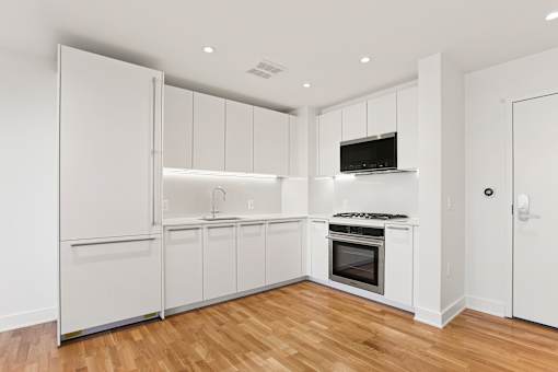 A kitchen with white cabinets and a wooden floor.
