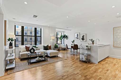 A living room with a white sofa set and a wooden floor.