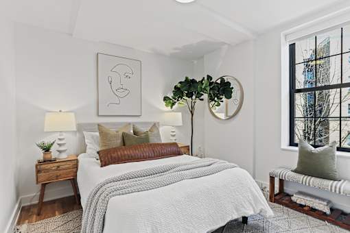 A bedroom with a large bed and a window overlooking a city.