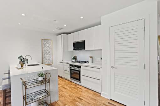 A kitchen with white cabinets and a white island with a sink.