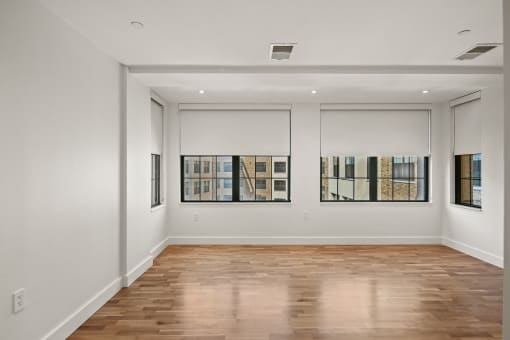 the living room of an apartment with white walls and wood floors