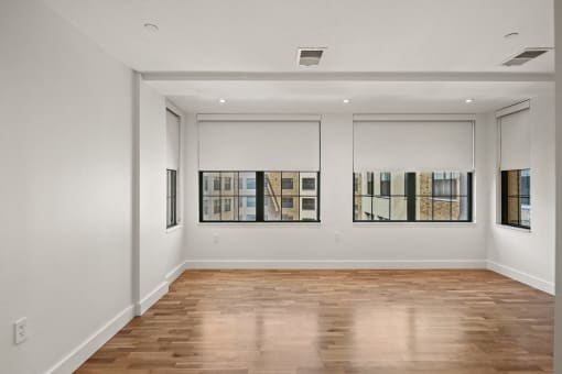 the living room of an apartment with white walls and wood floors