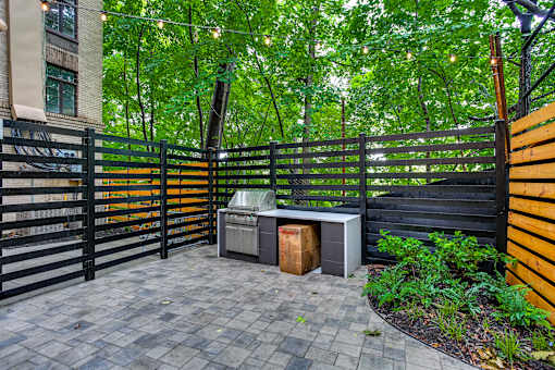 A black gate with a yellow stripe is in front of a green tree.
