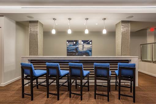 A bar with blue chairs and a painting on the wall.