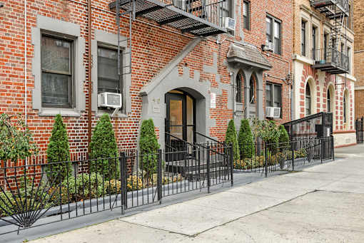 A row of red brick houses with black iron fences in front.