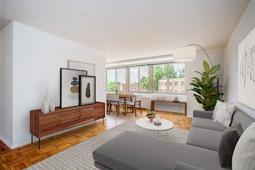 A living room with a grey couch, a wooden cabinet, a coffee table, and a large window.