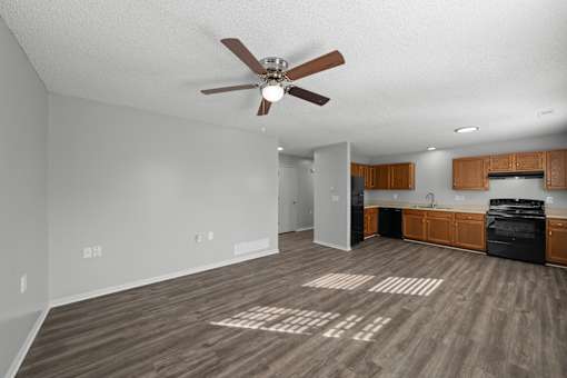 A spacious room with a ceiling fan and wooden flooring.