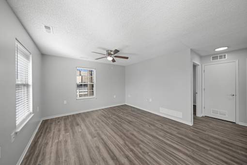A room with a ceiling fan and a window with blinds.
