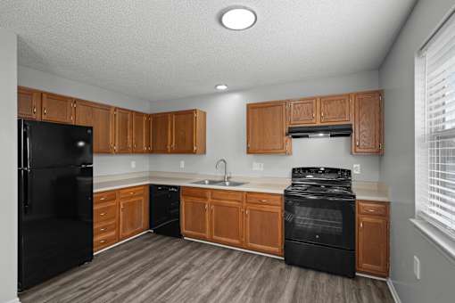A kitchen with black appliances and wooden cabinets.