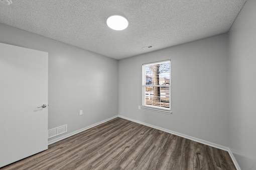 A room with a window and wooden flooring.