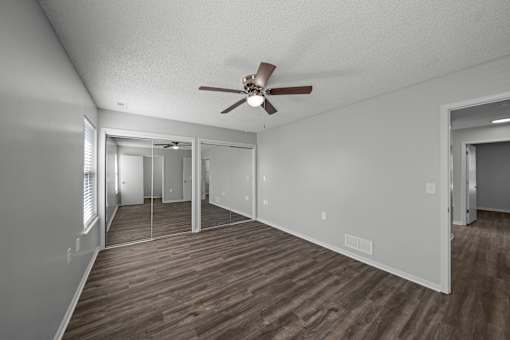 A room with a ceiling fan and wooden flooring.