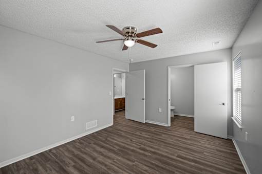 A room with a ceiling fan and wood flooring.