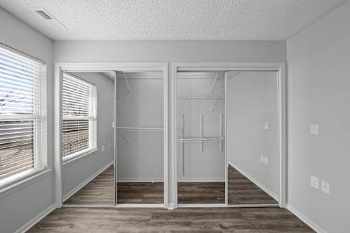 A room with a walk-in closet and a window with blinds.