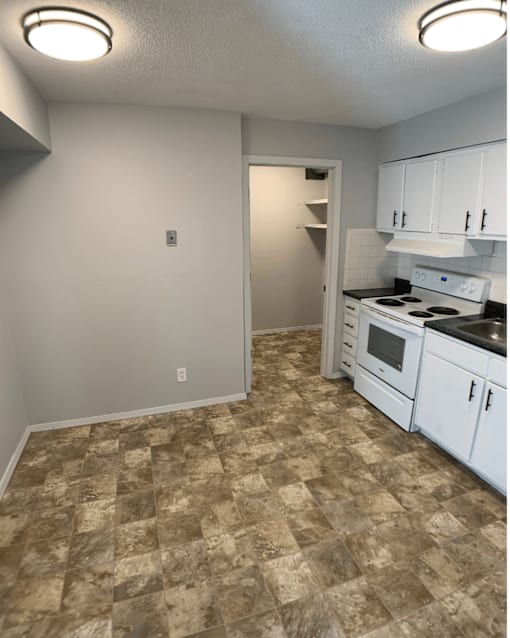 A kitchen with a tile floor and white cabinets.