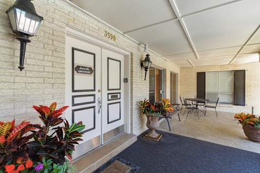 A front porch with a black door and a sign that says "3590".