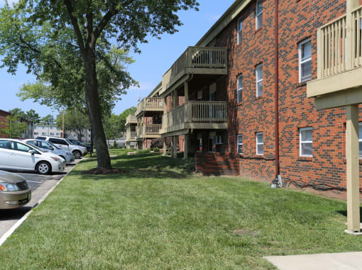 a grassy area with a tree in front of a brick building