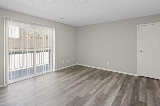 an empty living room with wood flooring and a large window