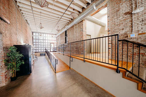 A long hallway with a black railing and a brick wall.